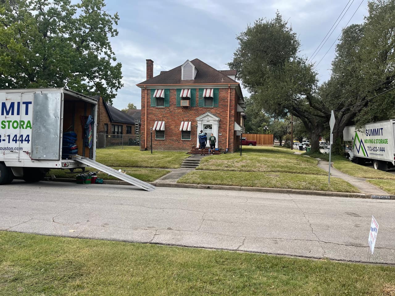 A Summit truck with its ramp down while the crew works at a two-storey brick house